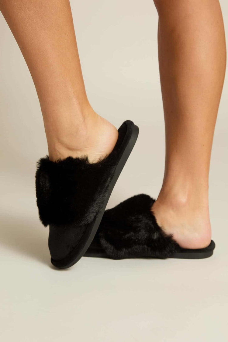 Black furry slipper mules showing side profile and thick plush faux fur strap